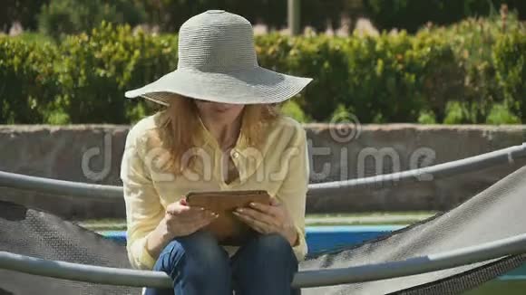 戴帽子的金发美女在户外吊床上放松视频的预览图