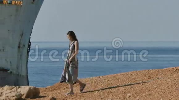 女人走在岩石上废弃的船附近视频的预览图