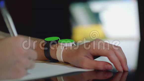 年轻的白人女孩同时一只手按在两只手表的绿色屏幕上关闭视频的预览图