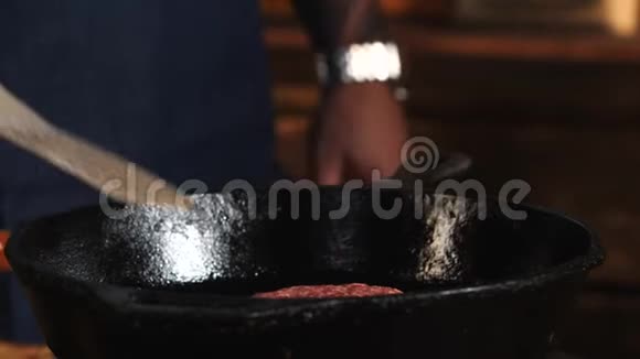 围着蓝色围裙的厨师站在平底锅烤架旁边为汉堡包煎炸库存数据视频的预览图