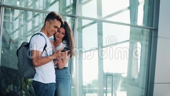 美丽可爱的情侣站在机场或火车站附近他们用智能手机指着她的手指视频的预览图