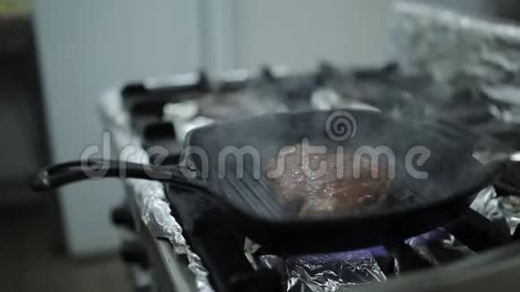 一个厨师在一家餐馆的厨房里用热的烤炉和牛排煎视频的预览图