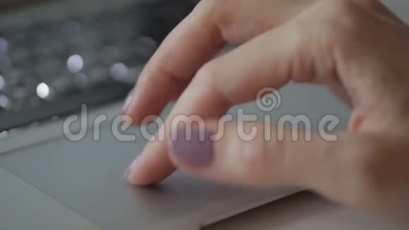 年轻女子正在室内桌旁用手指触摸笔记本电脑的触摸板视频的预览图