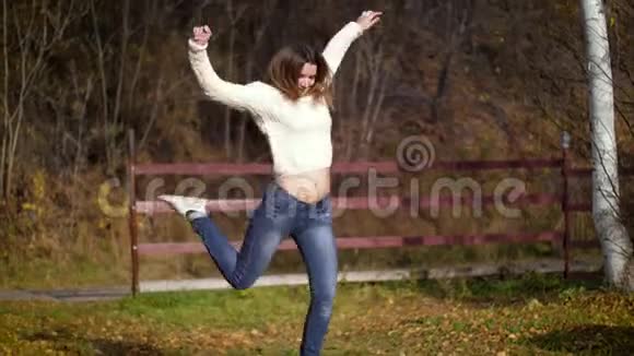 一个女人在秋天踢树叶到处都是女孩踢在一堆干燥的秋叶上4k60fps视频的预览图