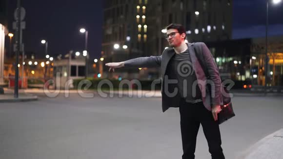 一位年轻的商人试图在夜街拦住一辆车视频的预览图