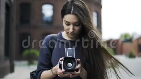 美丽的黑发女孩正拿着老式的照相机在街上视频的预览图