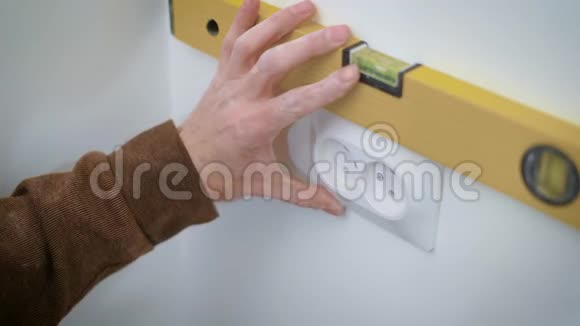 钢丝匠正用螺丝刀将一个双插座安装在一个扁平的白色墙壁上对准并拧动螺栓视频的预览图