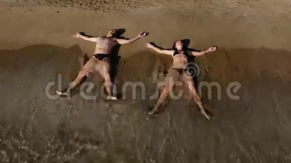两个年轻人在海滩上放松海浪拍打着身体视频的预览图