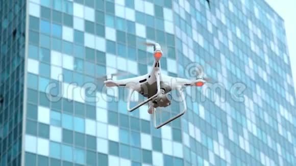 在一座工业商业大厦的背景下白色现代四翼飞机在城市里飞行和拍摄视频视频的预览图