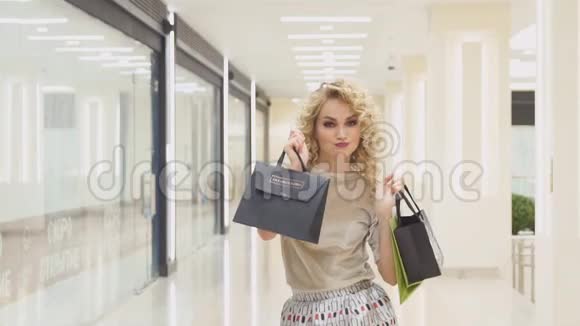 漂亮的女孩带着购物袋在商场里跳跃微笑着对他们的购买感到高兴视频的预览图