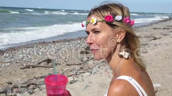 金发碧眼的女人坐在海边端着杯子喝酒视频的预览图