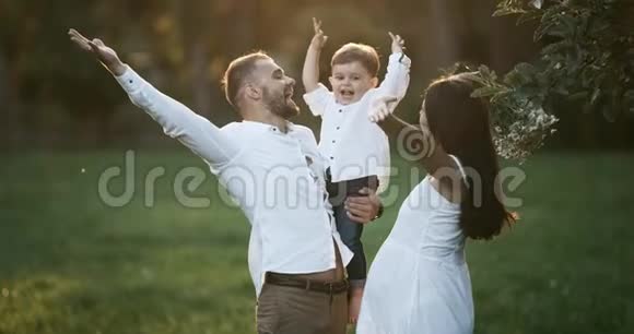 幼儿家庭家长与幼儿儿子玩耍快乐的爸爸妈妈抱着宝宝在户外微笑视频的预览图