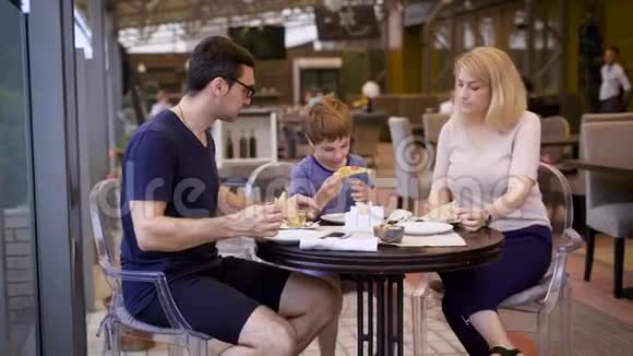 一个幸福的家庭在一家餐馆用餐一对夫妇点了一份披萨他们的小儿子对美味感到满意视频的预览图