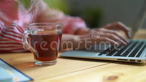 一个女孩在工作时喝茶坐在桌子旁一个透明的茶杯视频的预览图