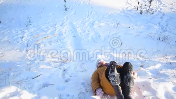 快乐的小女孩在冬天的公园里下雪一家人在一个下雪的公园里寒冷的晴天在山上滚动视频的预览图