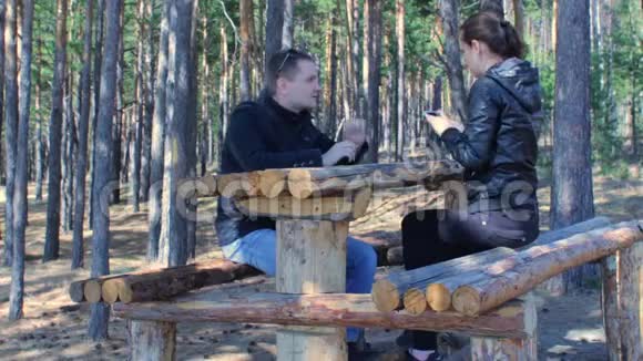 一对年轻夫妇在公园森林的长椅上坐着智能手机自拍视频的预览图