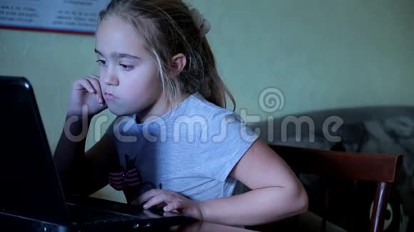 可爱的小女孩坐在电脑前用手机说话对小工具的依赖视频的预览图