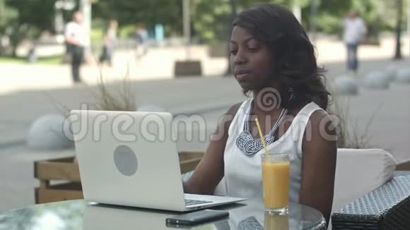 年轻的非洲妇女独自坐在一家咖啡馆里手提电脑上播放视频视频的预览图