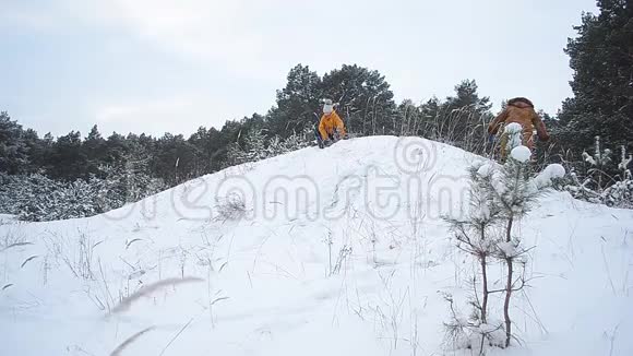 幸福的微笑女孩是在山上滚雪的冬天一家人走在白雪覆盖的冬天公园里视频的预览图