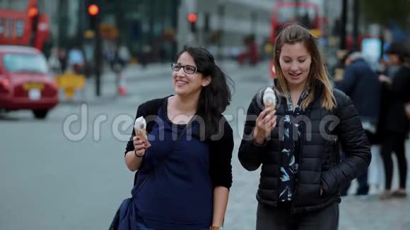 两个年轻女子慢吞吞地拿着冰淇淋穿过伦敦市视频的预览图