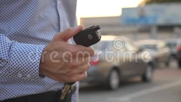 年轻的商人在室外停车场散步手里拿着车钥匙商人带着车钥匙的手臂盖盖视频的预览图