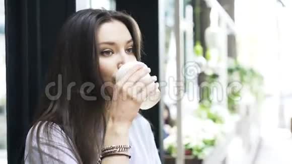 靠近一位年轻女子喝着咖啡微笑着面对观众视频的预览图