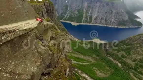 鸟瞰挪威的景观一个人坐在一块巨大的岩石的边缘背景是一座美妙的山视频的预览图