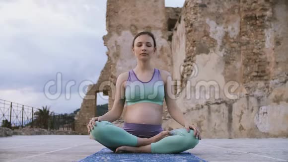 孕妇用莲花姿势做瑜伽未来的妈妈练习伸展运动视频的预览图