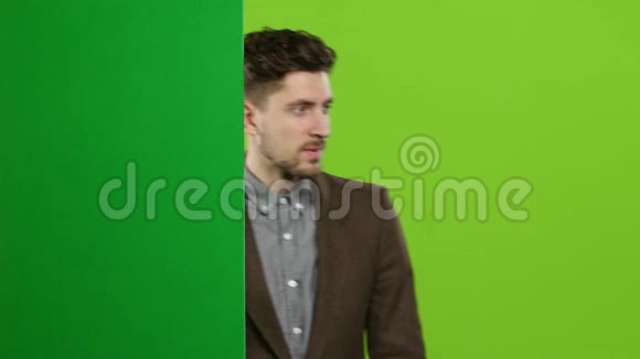 盖伊在广告中宣传产品从绿板后面往外看绿色屏幕视频的预览图