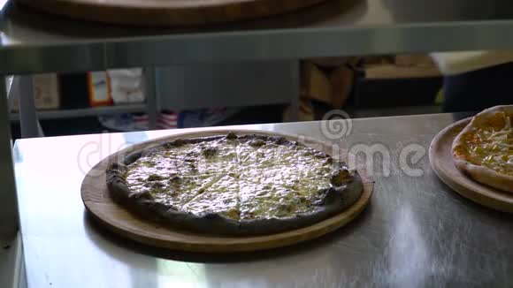 一个年轻的披萨师在餐厅的厨房准备披萨厨师把现成的热比萨饼和视频的预览图