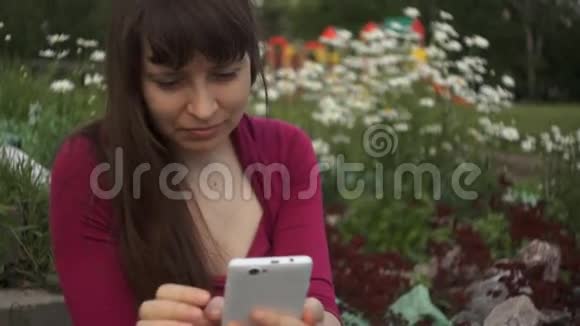 一个女人在雏菊的背景下用电话视频的预览图