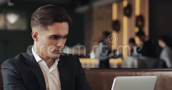 年轻商人坐在咖啡桌旁用笔记本电脑视频的预览图