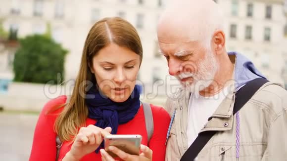 年长的父亲和他的小女儿站在街上使用智能手机幸福的家庭视频的预览图