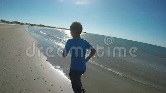 穿蓝色t恤的男孩在海边跑步视频的预览图