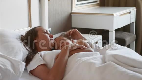 母亲和熟睡的孩子躺在床上在家里视频的预览图