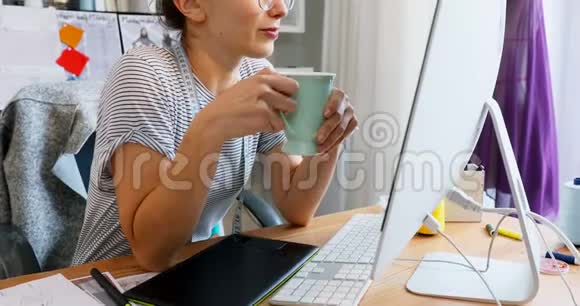女设计师在电脑工作时喝咖啡视频的预览图