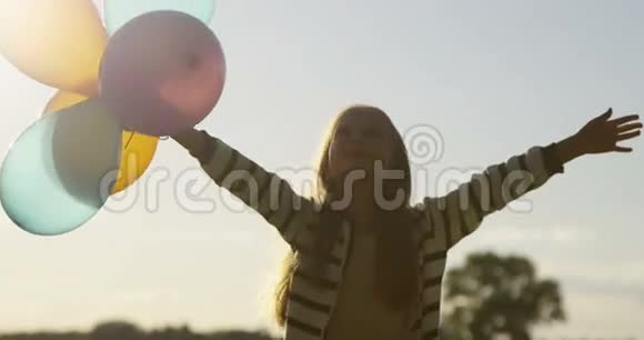 在野外背光区用彩色空气气球跳舞的小女孩视频的预览图