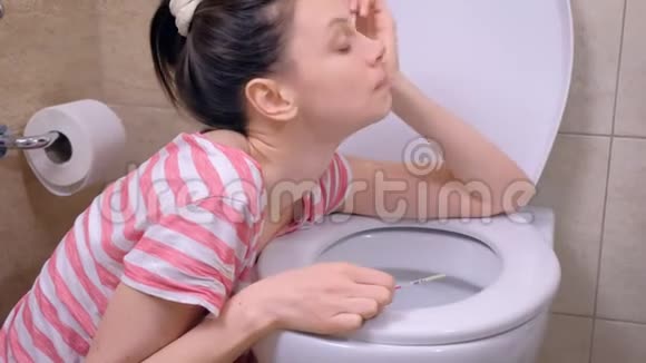 年轻的孕妇疲惫的女人疼痛是呕吐在厕所坐在地板上在家里视频的预览图