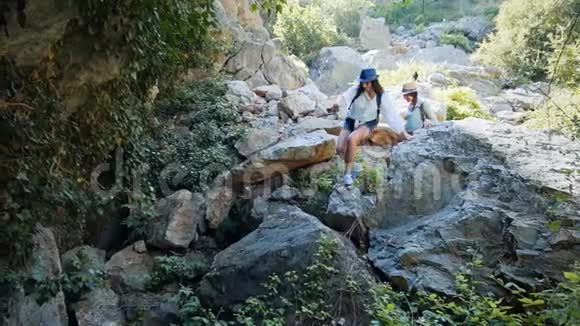 女旅行者帮助她的朋友爬上岩石视频的预览图