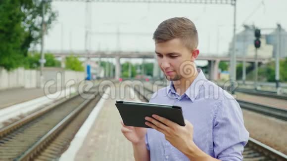 年轻人在火车站用平板电脑概念网上机票热爱旅游视频的预览图