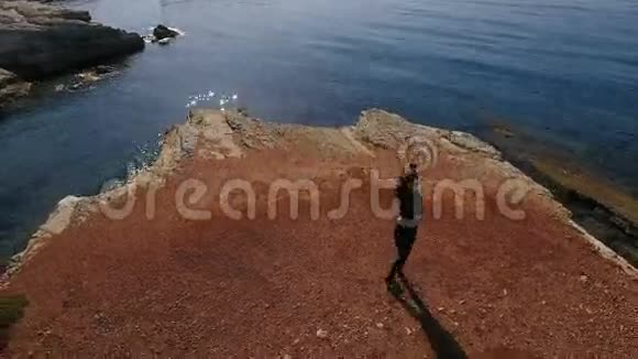 漂亮的女人在地中海附近的岩石上转过身视频的预览图