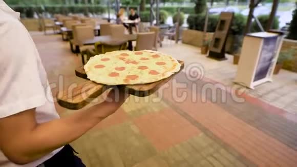 一位身穿白色衬衫的男侍应手为顾客带来美味的意大利热比萨饼小儿子的父母视频的预览图