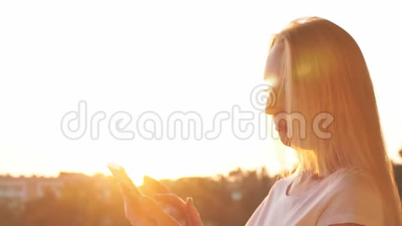 特写女性手在日落时使用智能手机慢动作视频的预览图