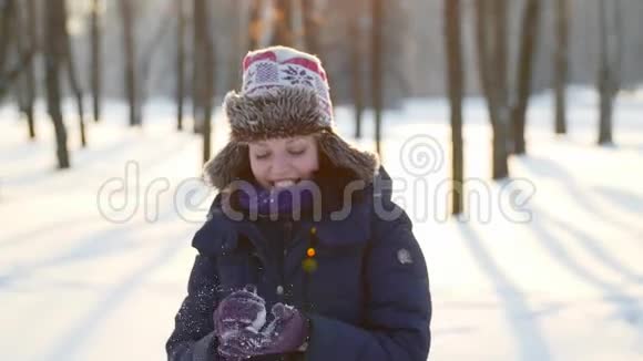 阳光明媚的冬天美丽的女人扔雪球快乐快乐快乐微笑视频的预览图