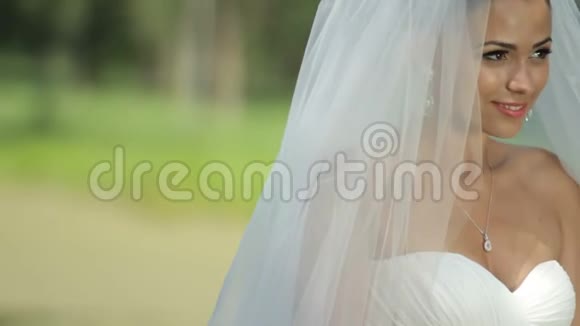 美丽的新娘拿着一束花在公园前面新婚快乐视频的预览图