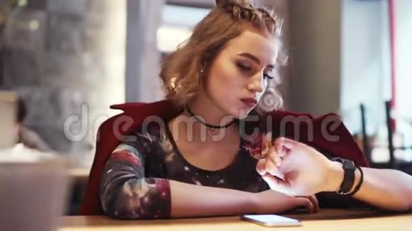 漂亮的金发女孩剪短头发看时间独自坐在咖啡馆里上网视频的预览图