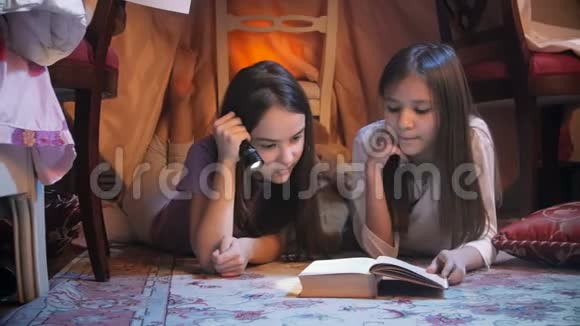 两个穿睡衣的女孩晚上在卧室里看童话书的特写镜头视频的预览图