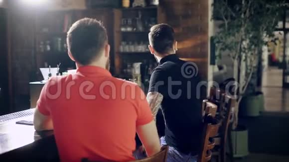 在酒吧柜台的咖啡馆里穿着休闲服装的年轻人的形象坐在桌旁的帅哥们站了起来视频的预览图
