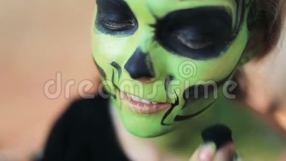 在万圣节化妆时女人用她的双手做了一个漂亮的面部艺术流苏绿色可怕的迷人骨架墨西哥视频的预览图