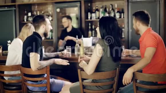 两对年轻夫妇坐在酒吧柜台喝饮料而酒吧服务员正在处理窗户案件视频的预览图